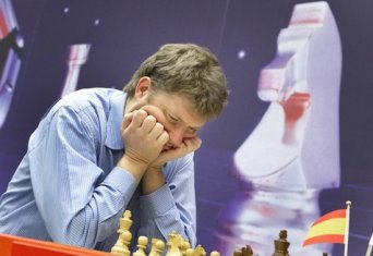 Alexei Shirov medirando ante el tablero con la cabeza entre las dos manos. En el fondo un caballo de ajedrez gigante decora la sala