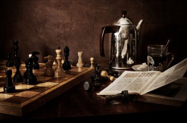 Mesa con un tablero de ajedrez, una cafetera y un libro de ajedrez abierto