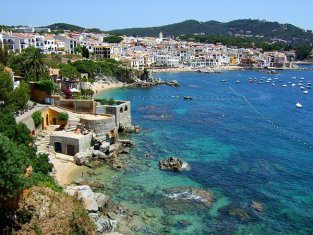 Vista de Calella. Se ve el mar azul lleno de embarcaciones y la playa, con el pueblo al pie de sta. Tambin una especie de pequea fortaleza en primer planp